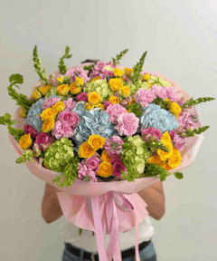 
                    
                      Colorful dopamine bouquet featuring blue hydrangeas, yellow spray roses, pink roses, carnations, and seasonal garden flowers.
                    
                  