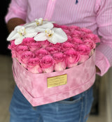 pink roses in a box shapes as heart with orchids on top
