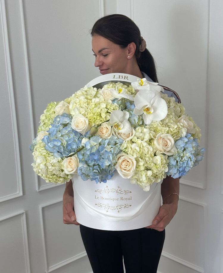 Hortensias y rosas de lujo en una caja hta con una mujer
