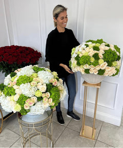 
                    
                      a person next to green and white flowers
                    
                  