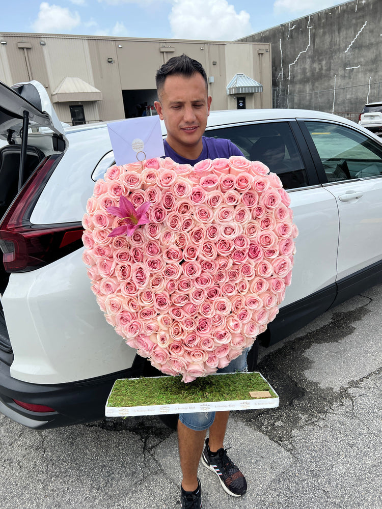 Corazón de rosas rosadas junto a un hombre