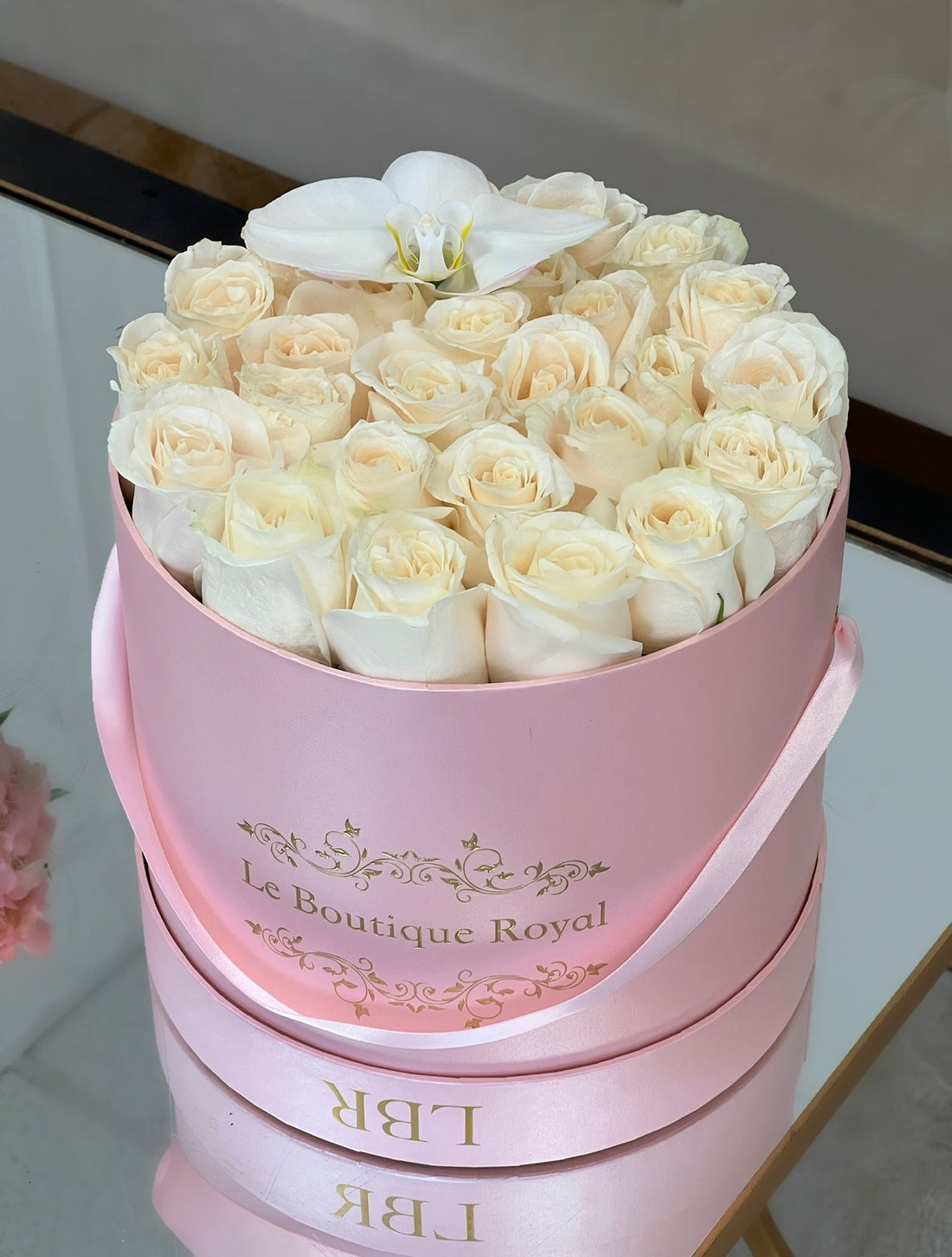 white roses with white orchid in a pink box