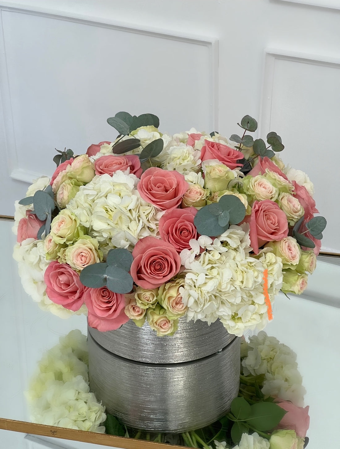 Flores rosadas y blancas en un jarrón plateado
