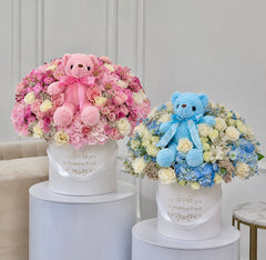 
                    
                      Arreglos florales para bebés en rosa y azul con ositos de peluche de Le Boutique Royal, perfectos para regalos de recién nacidos y celebraciones de revelación de género.
                    
                  